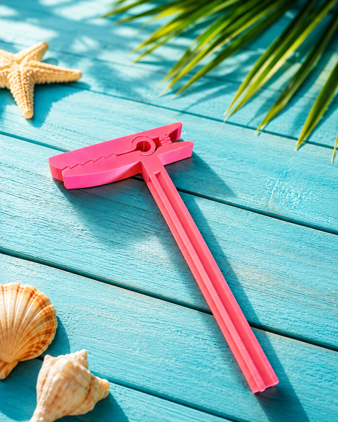 Pink beach towel clip on a turquoise wooden surface
